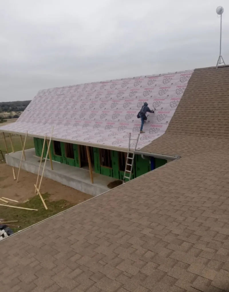 Worker preparing underlayment for a metal roof installation in Delta